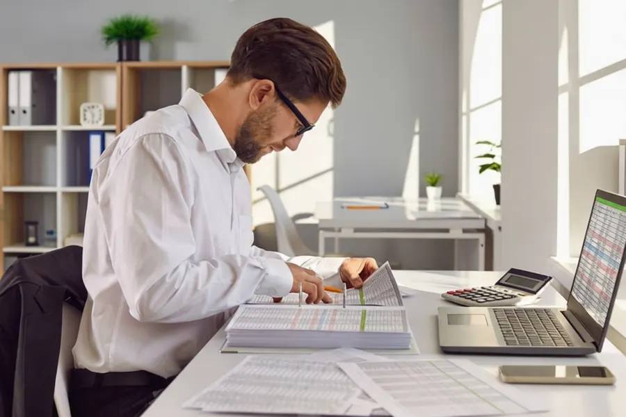 An HR manager reviewing an employment contract and social insurance contribution sheet alongside a foreign employee's work permit at a conference table