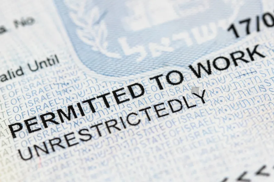 Residence permit renewal rejection letter on a desk next to an expired work permit card