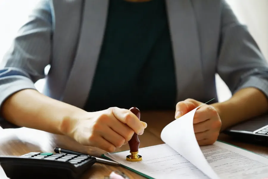 Tax inspector seated across from a company representative reviewing a compliance history folder in an interview room