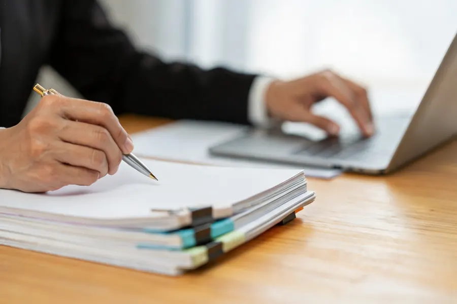 Advisor highlighting a conflict entry on a printed trademark search report while pointing to the conflicting registration date