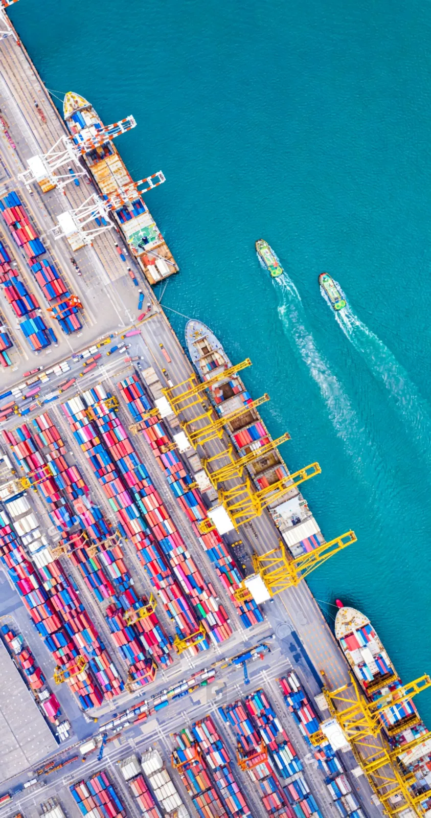 Aerial view of a busy container port with cargo ships and stacked shipping containers