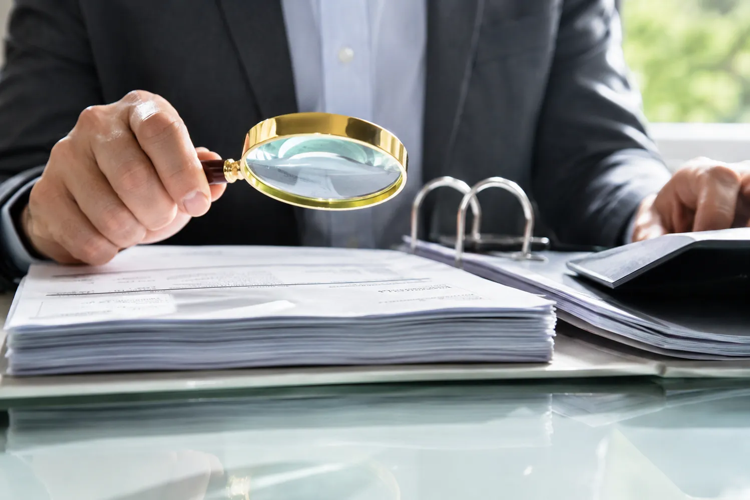 Business audit with magnifying glass reviewing trademark documents