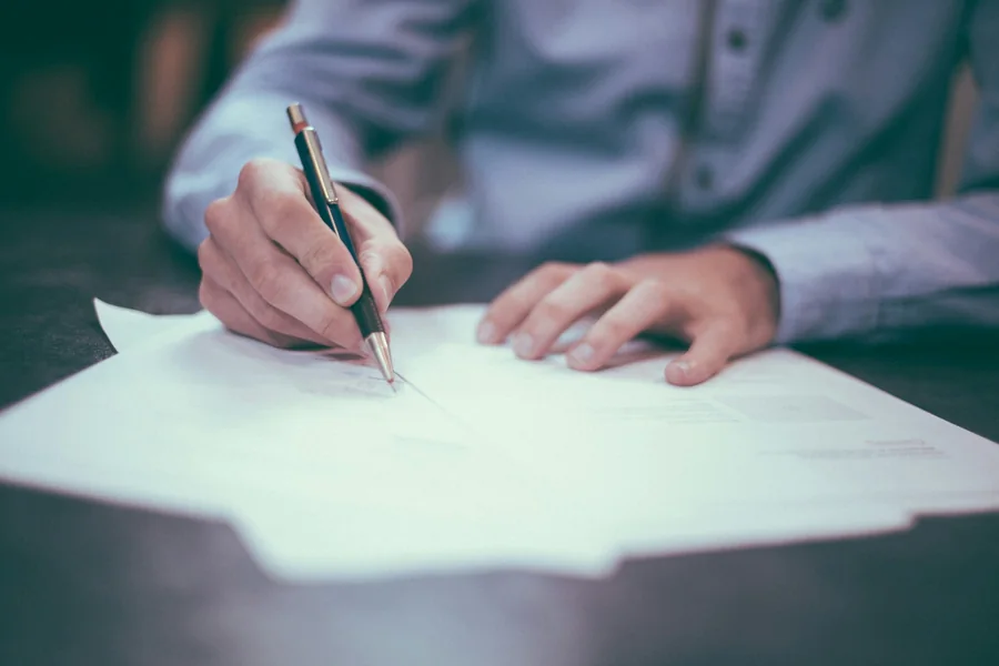 KYC review form on a desk with a checklist of document items and a red stamp marking the review as in progress