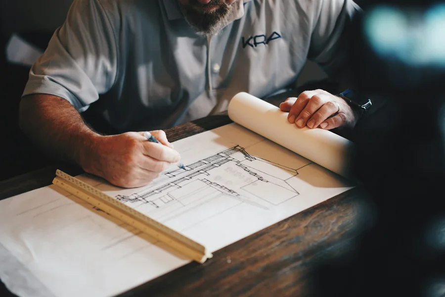 Patent engineer reviewing product technical drawings on a drafting table with a patent application form visible beside them